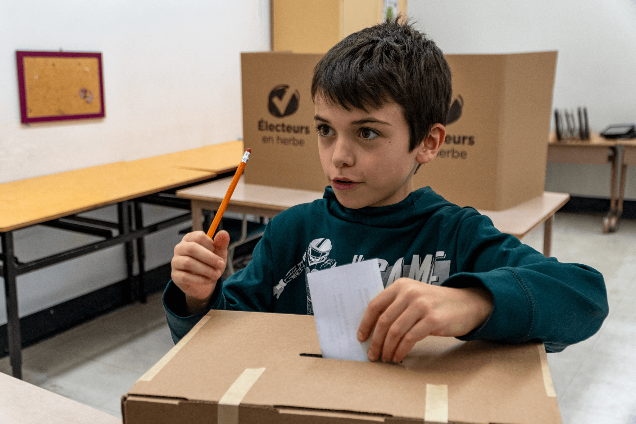 Un enfant déposant son bulletin de vote dans une urne.