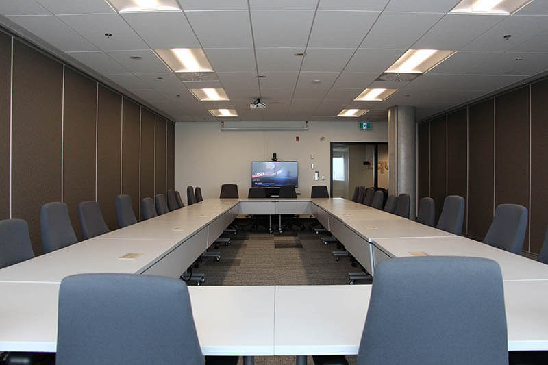 Grande salle de travail avec plusieurs tables positionnées en rond de façon à permettre les interactions entre les membres du personnel.