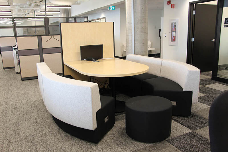 Banquettes et table de travail dans un espace ouvert pour le travail collaboratif.